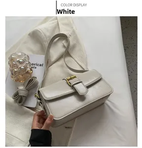 Detail of minimalist white crossbody bag featuring a large gold metal buckle decoration
