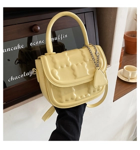 Close-up of yellow PU leather crossbody bag with embossed floral texture and metal chain