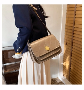 Detail of a beige quilted crossbody bag with golden round twist lock and flap design