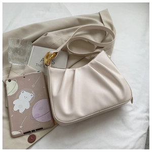 Detail of beige pleated hobo bag with gold chain link on neutral fabric background