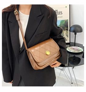 Detail view of brown quilted crossbody bag with vintage gold buckle and leather strap