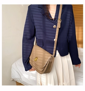 Detail of khaki quilted crossbody bag with golden circular twist lock on a model
