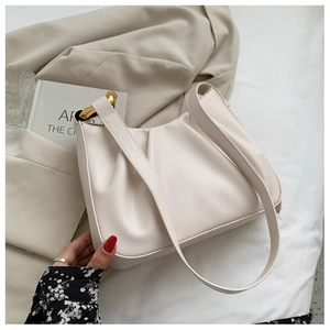 Detail of creamy gathered bucket bag featuring premium gold metal ring hardware on soft fabric