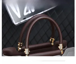 Détail des poignées en cuir à motif litchi et de la ferrure dorée sur le sac à main