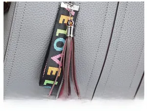 Détail du sac en cuir gris avec pendentif LOVE coloré et gland en cuir marron