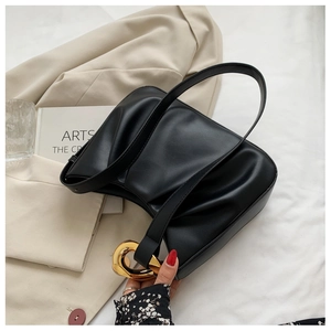 Close-up of matte black pleated cloud bag with oversized gold metal buckle detail