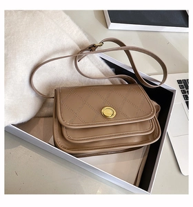 Detail of brown quilted crossbody bag with gold twist lock and accordion structure