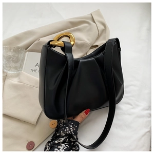Detail of black cloud bucket bag with pleated texture and matte gold chunky chain link