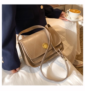 Close-up of khaki quilted crossbody bag with golden rotary clasp and accordion pleats