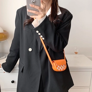 Mini sacoche orange à damier portée par un mannequin dans un cadre intérieur élégant