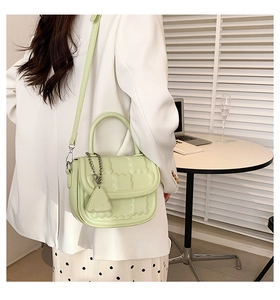 Close-up of pistachio green crossbody bag with embossed bear texture and metal chain