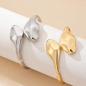 Minimalist snake-shaped open rings in gold and silver finish on a display stand