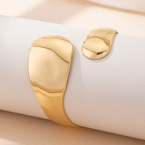 Modern gold curved open bangle with a polished mirror finish and organic fluid design