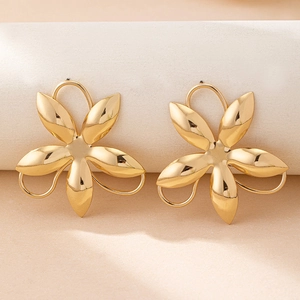 Detailed close-up of 3D golden flower earrings with glossy metallic finish and hook backs