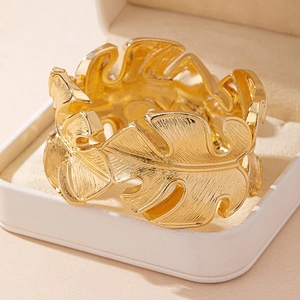 Golden open cuff bracelet with brushed monstera leaf design in a soft jewelry box