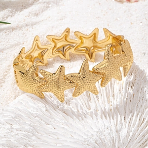 Golden starfish cuff bracelet for women featuring textured seaside charms and beach style