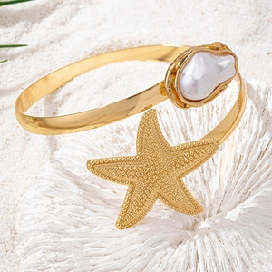 Bracelet de bras étoile de mer dorée avec perle baroque sur corail et sable