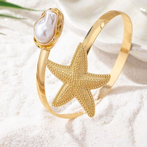 Gros plan détaillé d'un bracelet de bras doré avec étoile de mer et perle baroque chic