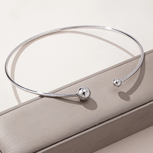 Minimalistisches Silberhalsband mit Metallkugeln auf einer grauen Schmuckschatulle
