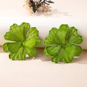 Close-up of green statement flower earrings with detailed pleated texture and wavy edges