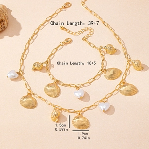 Golden shell and heart pendant necklace and bracelet set on a beach sand background