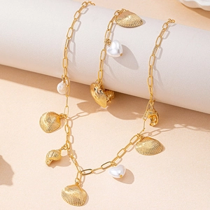 Golden ocean style necklace with shell charms and white heart pearls on a white display