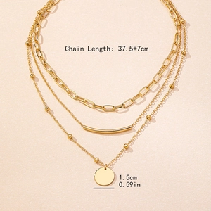 Gold layered necklace set featuring paperclip chains and a polished round pendant charm