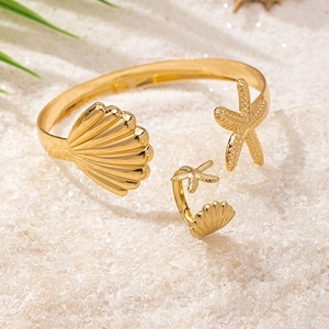 Close-up of golden starfish and seashell jewelry set on white sand beach background