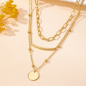 Detail of gold multi-layered necklace with paperclip chain and round disc pendant
