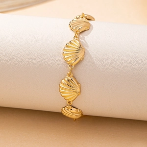 Golden shell bracelet with radiant texture on white jewelry display for women