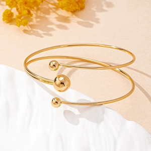 Detail of a minimalist gold-plated spiral bangle with three polished spherical beads