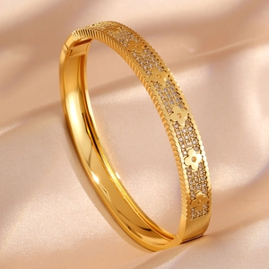 Gold plated clover bracelet with pave set crystals on silk background
