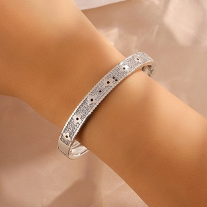 Close-up of a silver-toned bangle with sparkling pavé zircons and clover floral motifs
