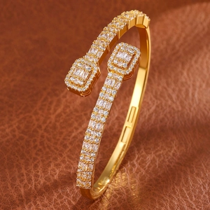 Detail of gold-plated open bangle featuring geometric ends and pavé-set clear zircons