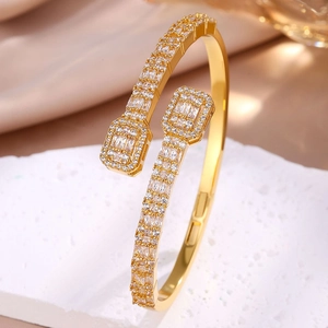 Macro detail of gold open bangle featuring geometric square ends and pavé set crystals
