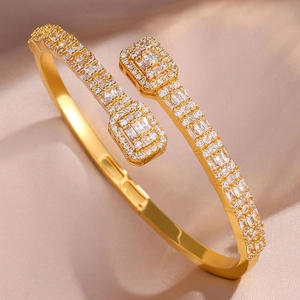 Detailed side view of gold open bracelet with rectangular and round clear zircons