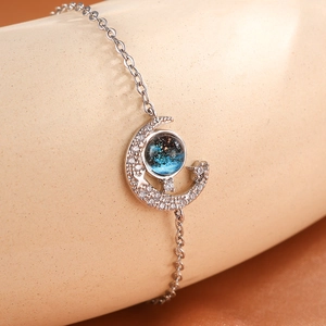 Macro view of silver crescent moon bracelet featuring sparkling crystals and star sand bead