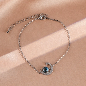 Close-up of silver star and moon bracelet with blue planet bead on champagne silk