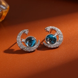 Detailed macro view of silver moon earrings with blue star stone and zircon stones