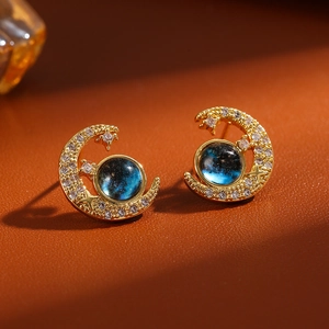 Macro view of gold moon earrings with galaxy blue stone and sparkling zircons