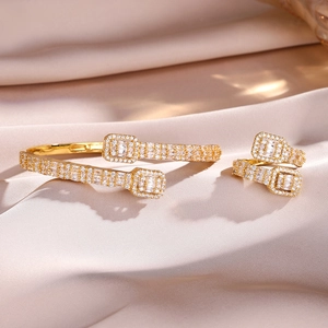 Detail of gold-plated open bangle and ring set with pavé cubic zirconia on satin cloth