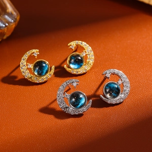 Macro view of gold and silver moon and star earrings with blue starry nebula stones