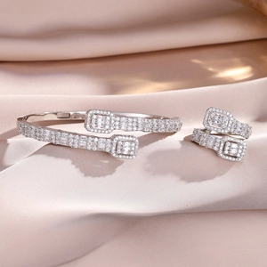 Close-up of silver open bracelet and ring set with pavé cubic zirconia on pink silk