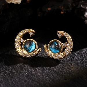 Detail of crescent moon earrings with blue sandstone inlay and gold plated crystals