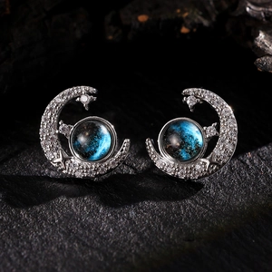 Macro shot of silver crescent moon earrings with blue sandstone and sparkling zircons
