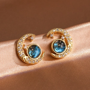 Macro detail of crescent moon earrings with blue starry galaxy stone and crystal pavé