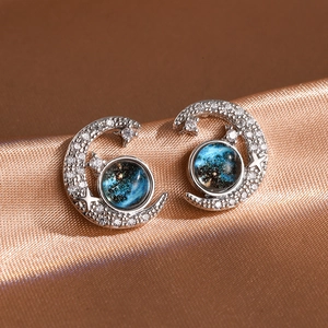 Macro detail of crescent moon earrings with blue star stone and glittering zircon stones