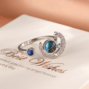 Macro shot of silver open ring with blue galaxy stone and pavé moon and star charms