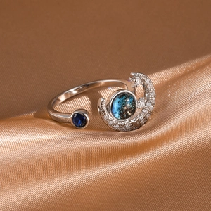 Detail of silver-tone open ring featuring moon design and blue sand stone on satin