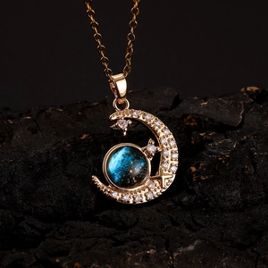 Macro shot of gold-plated crescent moon necklace with blue nebula bead and crystals